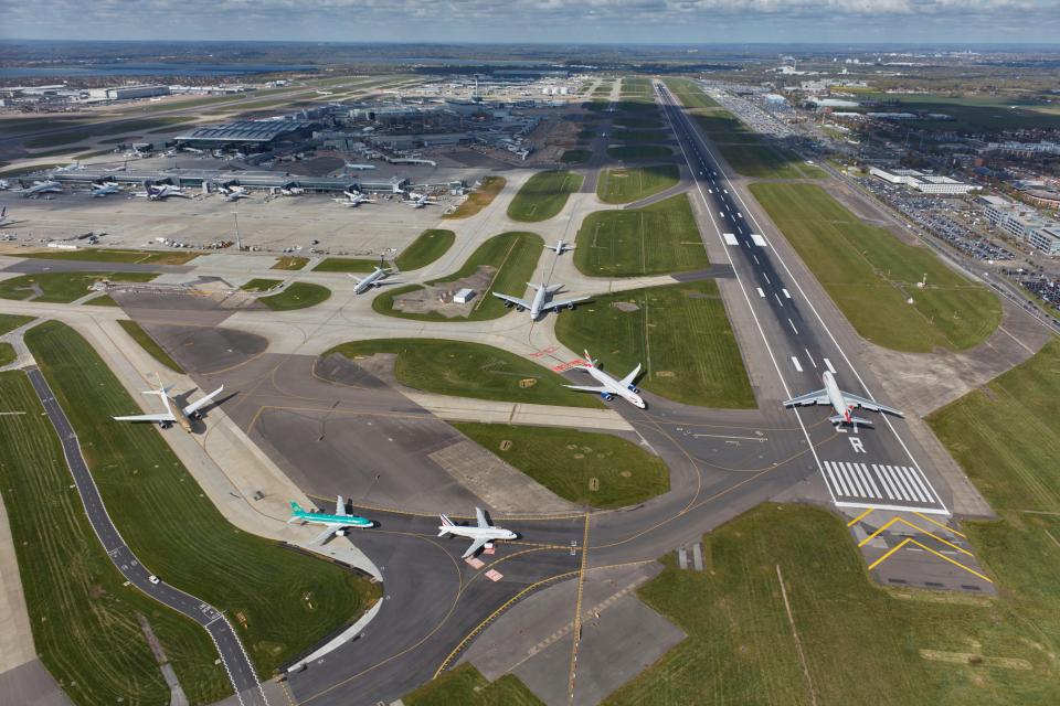 Aerial view of Heathrow Airport showing runways, taxiways, terminals, and parked aircraft.