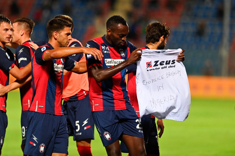 Crotone's Simy holds up a shirt that reads "End Police Brutality in Nigeria."