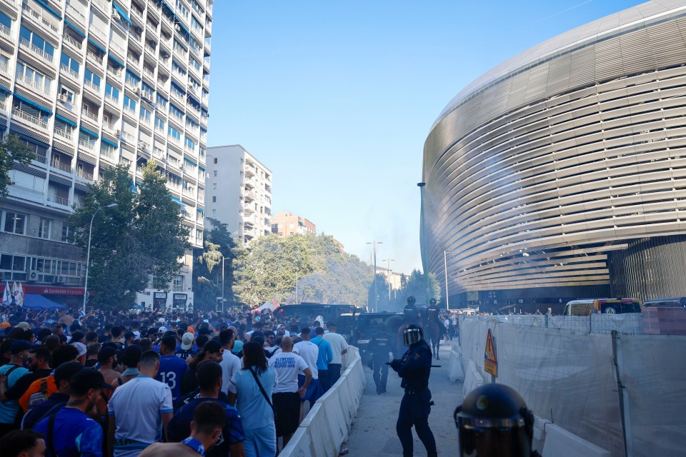 Supporters of Olympique de Marseille arriving at the Santiago Bernabeu stadium, with police presence.