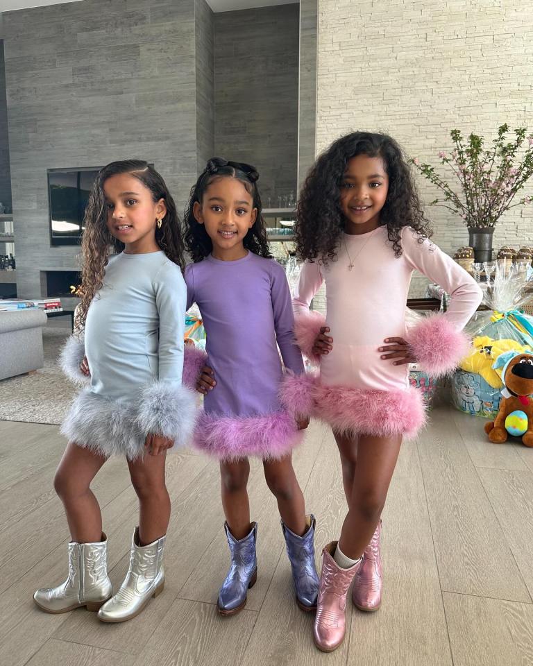 Three young girls in pastel dresses with feathered trim and cowboy boots.