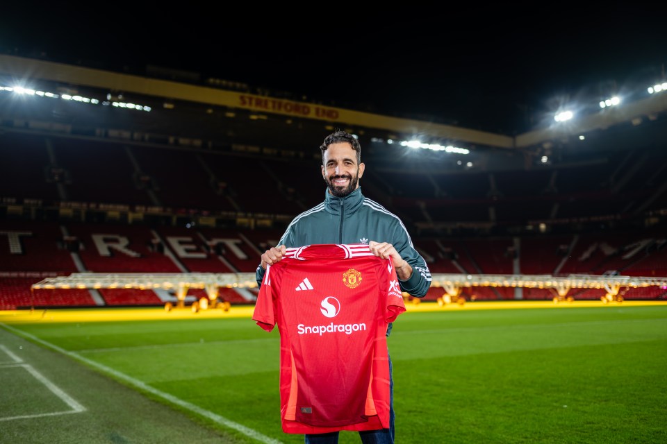 Ruben Amorim holding a Manchester United jersey at Old Trafford.