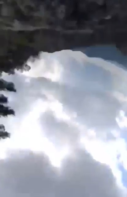A video still showing a cloudy sky and mountains.