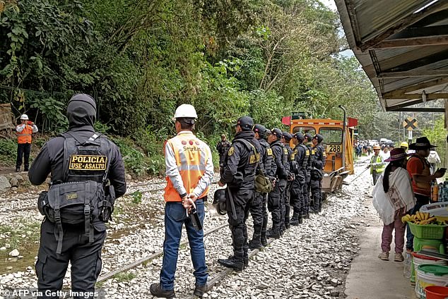 At least 900 tourists were left stranded near Machu Picchu after protestors blocked the train tracks that lead to and from the ancient Inca city (pictured: police along the tracks on Tuesday)