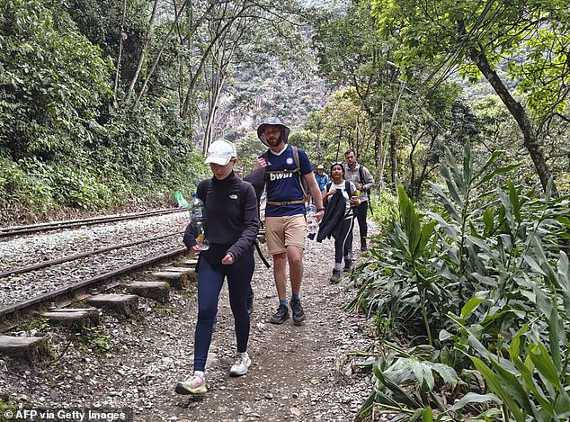 Those stuck in the town claimed authorities told them to trek several hours to catch a train or bus outside of the Machu Picchu region (pictured: tourists walking along the tracks on Tuesday)