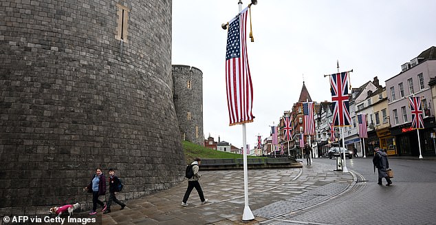 People walk under US flags outside Windsor Castle, in Windsor, on September 17, 2025, during US President Donald Trump's second State Visit to the UK. US President Donald Trump arrived in Britain on Tuesday for an unprecedented second state visit, with the UK government rolling out a royal red carpet welcome to win over the mercurial leader. (Photo by Paul ELLIS / AFP) (Photo by PAUL ELLIS/AFP via Getty Images)