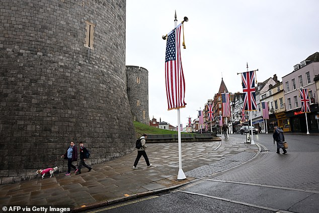 People walk under US flags outside Windsor Castle this morning as the state visit begins