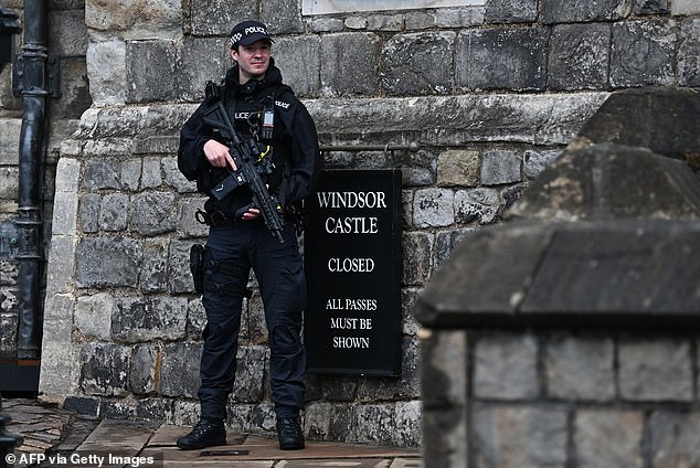 An armed police officer holds his weapon as he stands guard outside Windsor Castle today