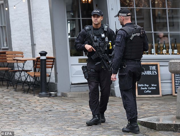 An armed police officer holds his weapon as he stands guard outside Windsor Castle today
