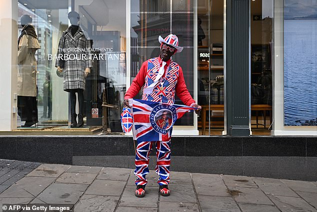 A royal supporter poses for photos next to Windsor Castle this morning