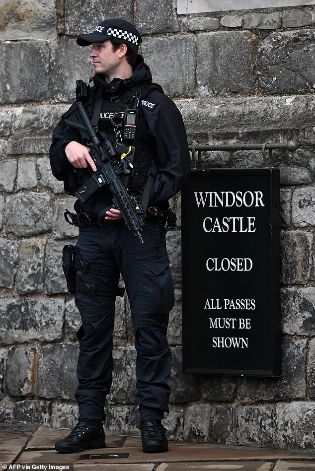 An armed police officer holds his weapon as he stands guard outside Windsor Castle today