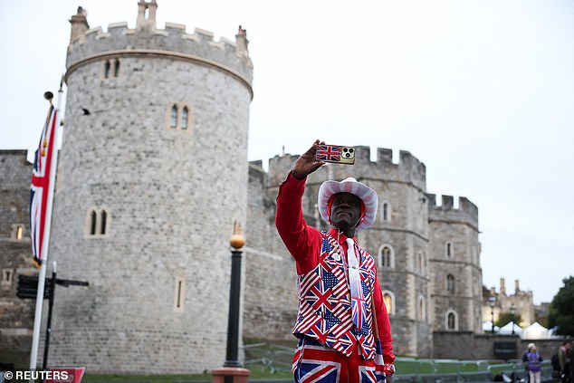 A man in a Union Jack suit takes a selfie outside Windsor Castle this morning