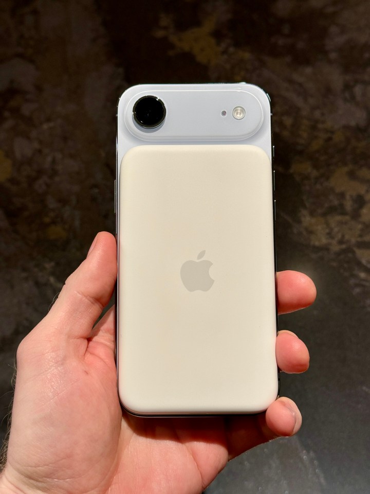 Hand holding an iPhone with a MagSafe battery pack attached to the back.