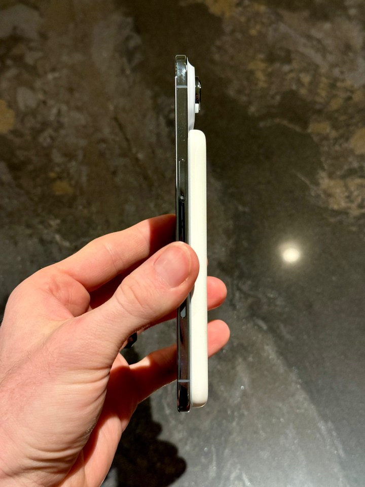 Hand holding an iPhone with a white iPhone Air attached to the back.
