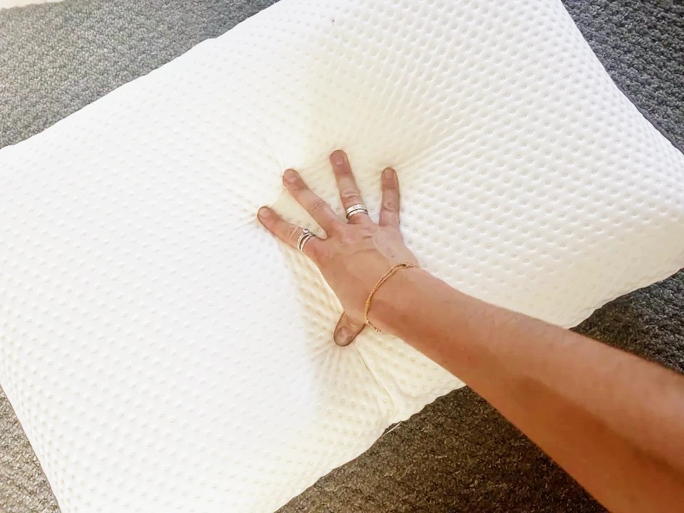 Hand pressing on an Emma Premium foam pillow.