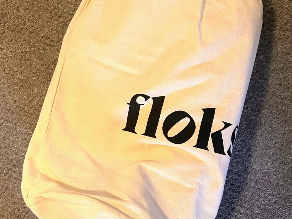 Floks wool pillow in a beige fabric bag.