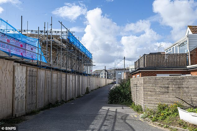 The huge 8ft-high wall can be seen as part of the development (left), which is directly in front of Liz Bates' balcony (right)