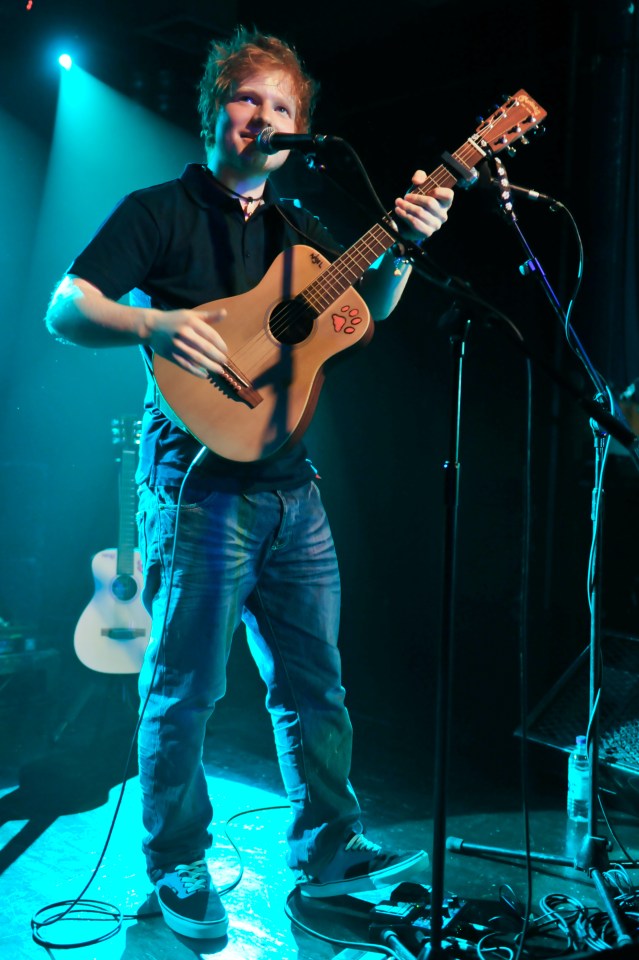 Ed Sheeran performing on stage with an acoustic guitar.