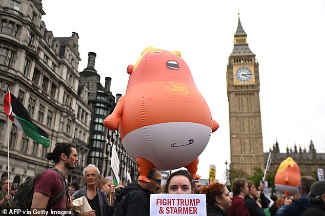 Protesters carry placards and a large inflatable orange baby as they march through Parliament Square with the Houses of Parliament in the background in London on September 17, 2025 during a national march organised by the Stop Trump Coalition against the State Visit of US President Donald Trump. US President Donald Trump arrived in Britain for an unprecedented second State Visit, with the UK government rolling out a royal red carpet welcome to win over the mercurial leader. (Photo by JUSTIN TALLIS / AFP) (Photo by JUSTIN TALLIS/AFP via Getty Images)
