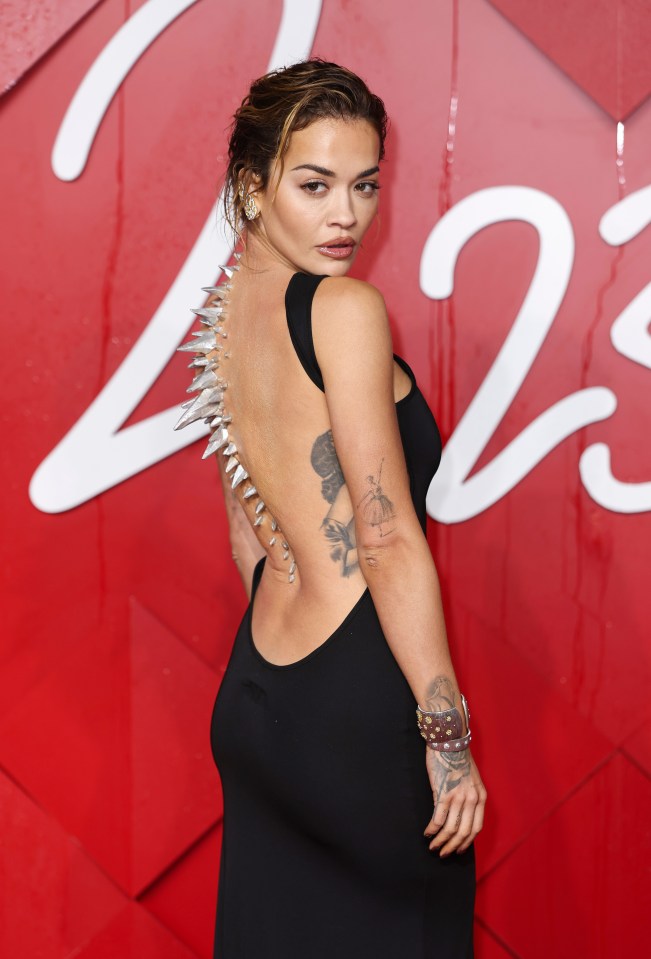 Rita Ora in a black backless dress with silver spikes on the back at The Fashion Awards 2023.