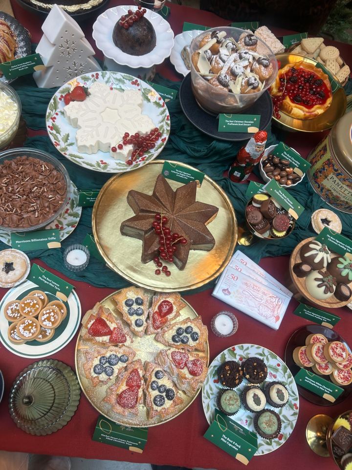 An array of Christmas desserts, including a chocolate star, profiterole bowl, trifles, tarts, cupcakes, and shortbread, displayed on red and green fabric.