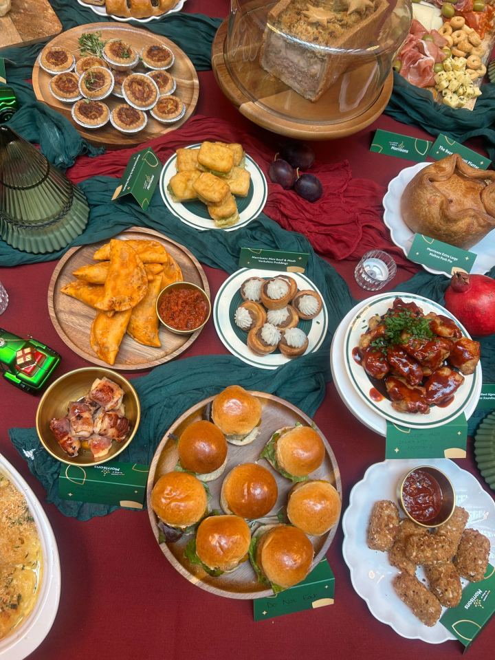 A banquet of various Morrisons brand foods, including mini quiches, a large pork pie, mini fish and chip batters, beef and mash Yorkshire puddings, chicken empanadas, chicken skewers, mini burgers, Korean fried chicken, and breaded sticks.
