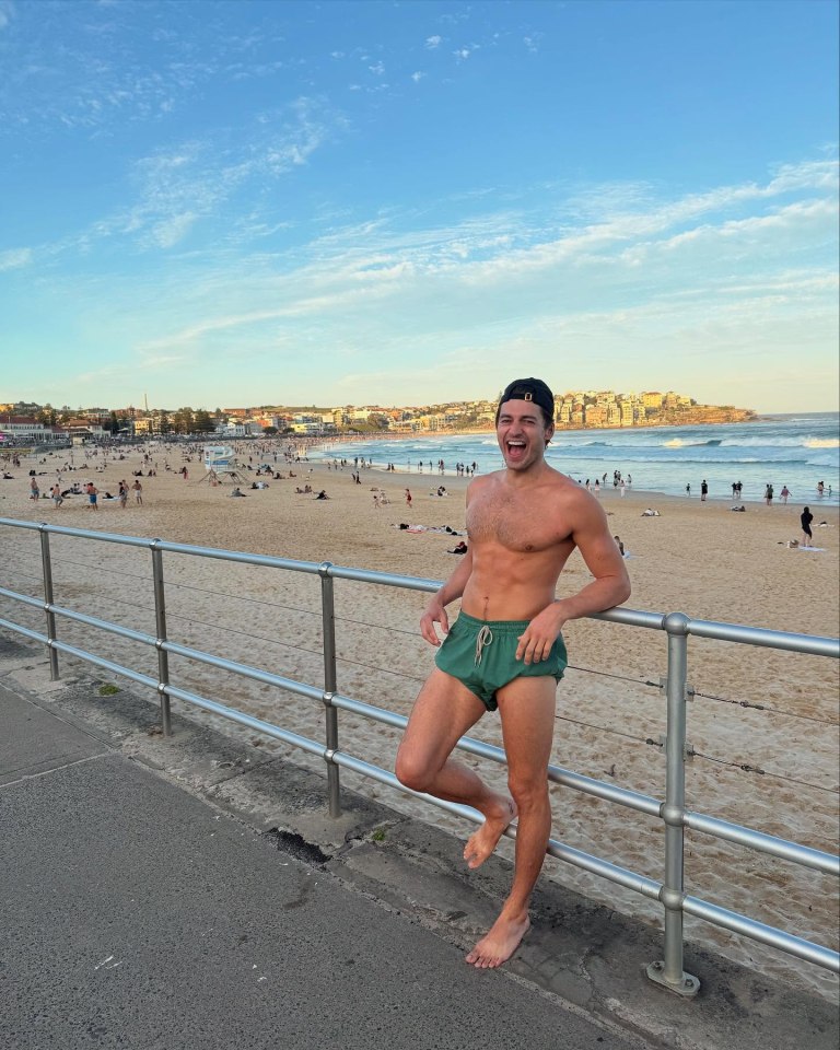Harry Johnson in green swim shorts laughing at the beach.