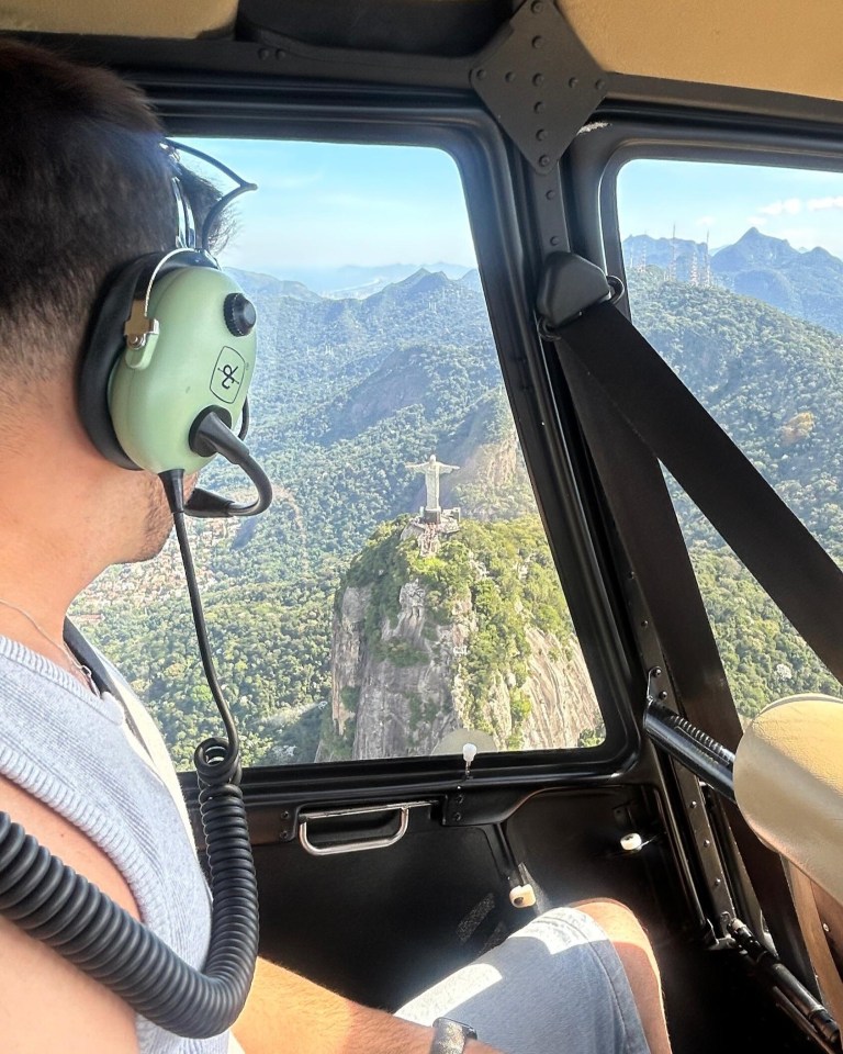 A man with aviation headphones looking out a helicopter window at the Christ the Redeemer statue in Rio de Janeiro.