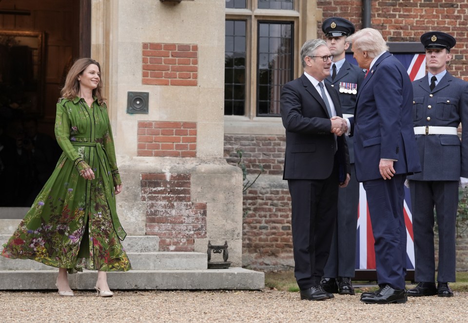 President Donald Trump shakes hands with British Prime Minister Keir Starmer as Starmer's wife Victoria Starmer stands nearby.