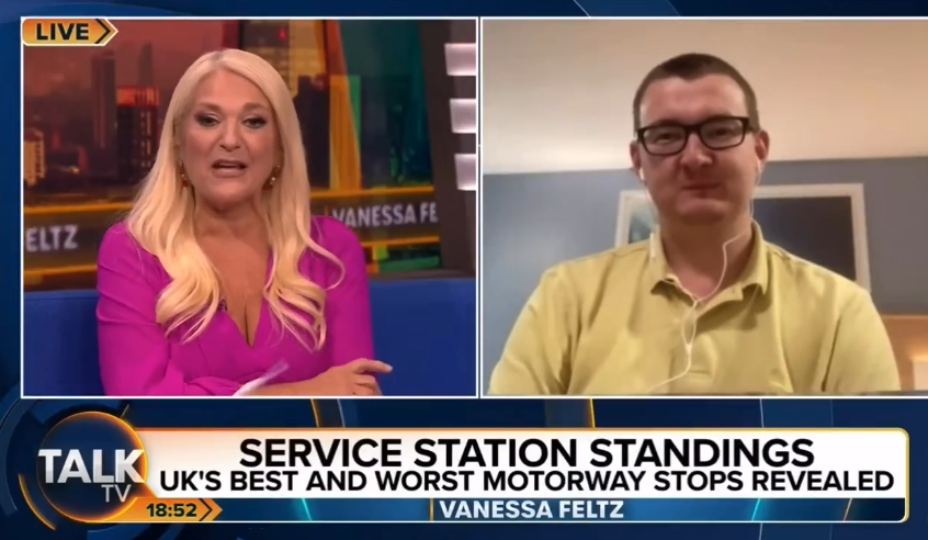 Two people, a woman with blonde hair in a pink top and a man in a yellow shirt and glasses, are visible in a split screen during a TV segment about UK service station rankings on Talk TV.