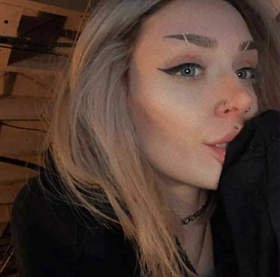 A young woman, Savanah White, with light blonde hair, eyeliner, and facial piercings, posing for a photo.
