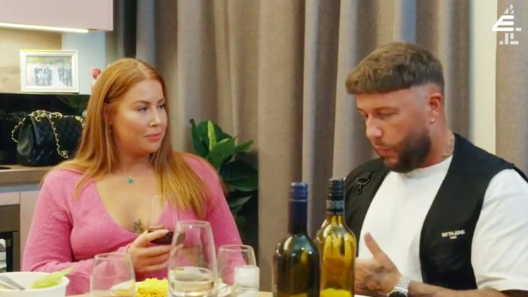 Polly's best friend and Adam talking at a table with bottles of wine.