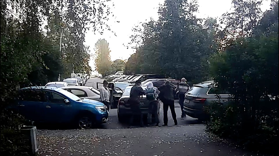 A group of people loading items into a car in a parking lot.