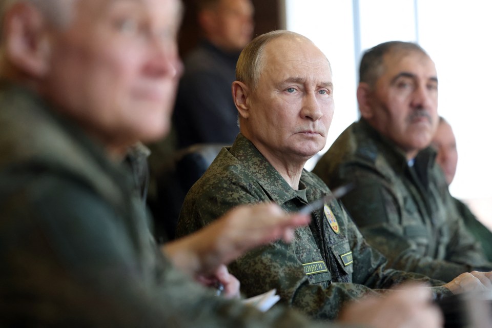 Vladimir Putin in military fatigues observing military drills.