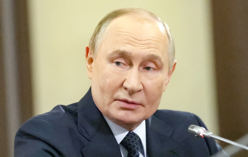 Russian President Vladimir Putin in a dark suit and spotted tie, looking slightly to his left during a meeting.