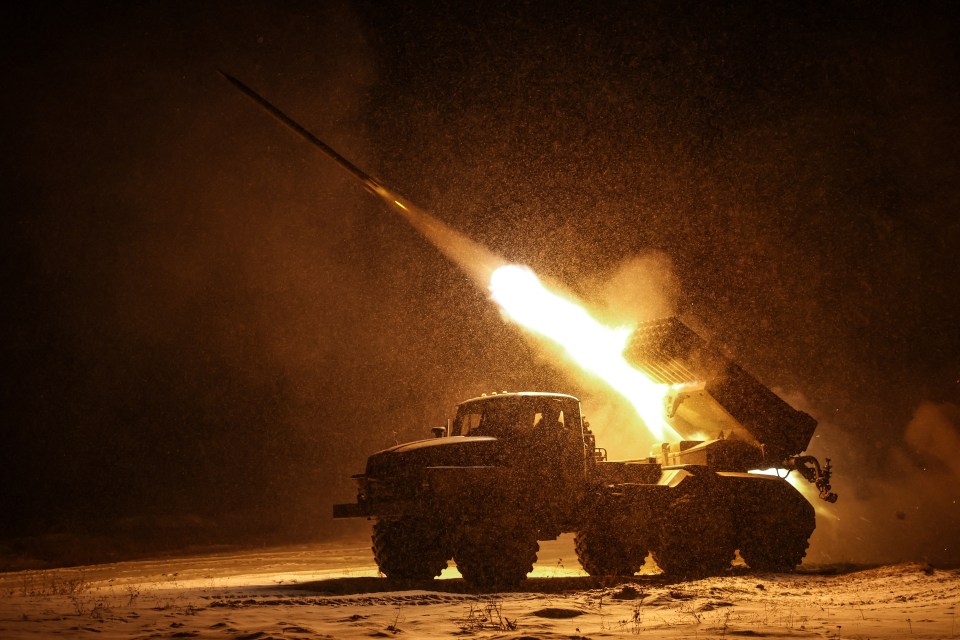 A Ukrainian BM-21 'Grad' multiple rocket launcher fires at night, with a rocket illuminating the snowy landscape.