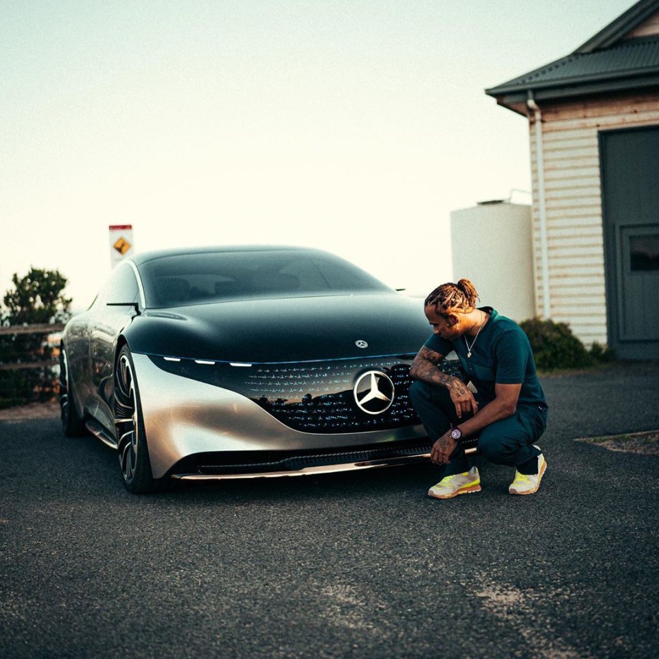 Lewis Hamilton crouching next to a Mercedes-Benz Vision EQXX.