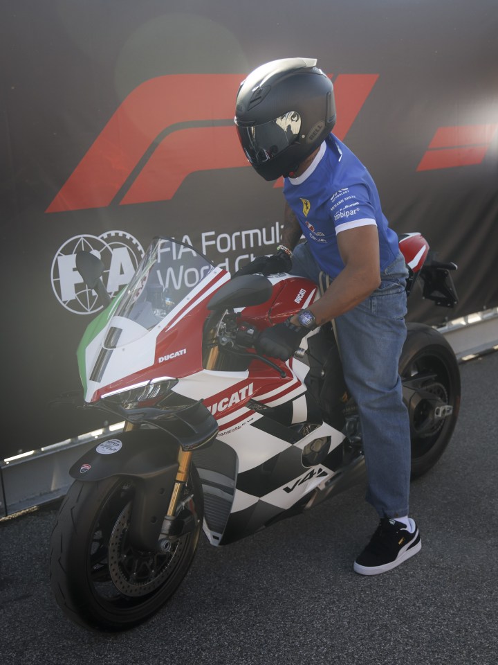 Lewis Hamilton riding a red motorbike through a crowd of fans.