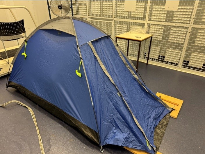 A blue and gray tent on a dark floor.