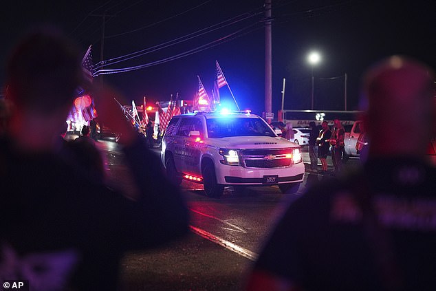 People are seen saluting as a York County sheriff vehicle drives past during a procession Wednesday night