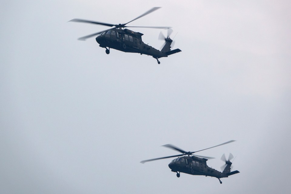 Two U.S. Army Black Hawk helicopters fly over the National Mall during a military parade.