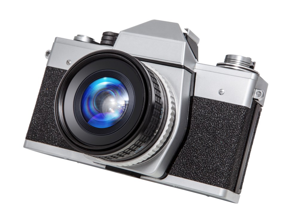 A silver and black SLR film camera with a prominent lens, angled slightly upwards.