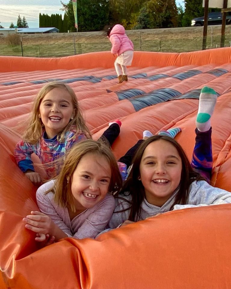 Three girls playing on a large inflatable.