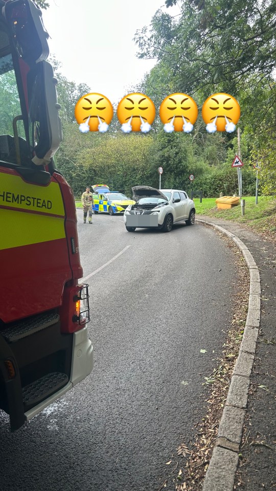 A fire truck and a police car at the scene of a car accident on a road.