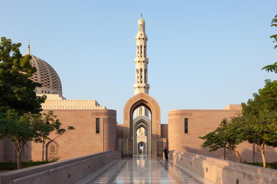 Sultan Qaboos Grand Mosque in Oman with a woman walking in the distance.