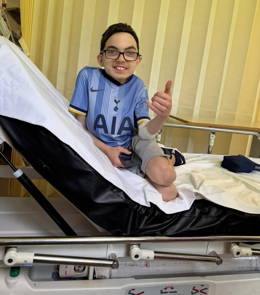 A 15-year-old boy in a hospital bed gives a thumbs-up.
