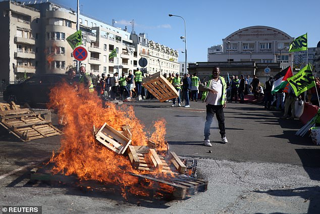 French SNCF railway workers on strike, holding Sud Rail labour union flags, gather near burning wooden pallets at Gare de Lyon train station in Paris as part of a day of nationwide strikes and protests against the government and cuts in the next budget