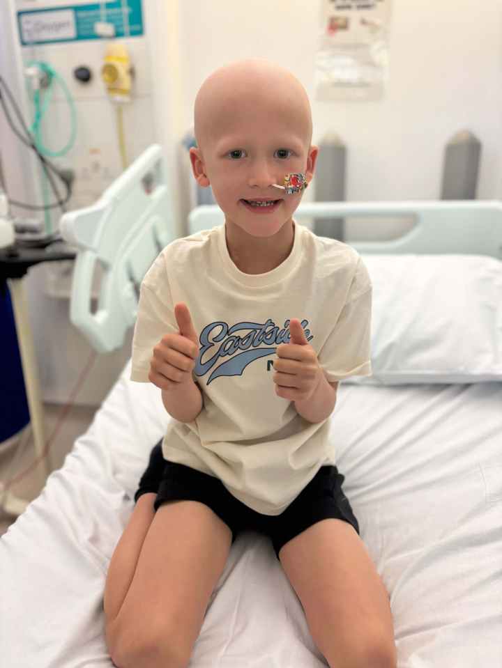 Tommy Verbickas, a young child with cancer, giving two thumbs up in a hospital bed.