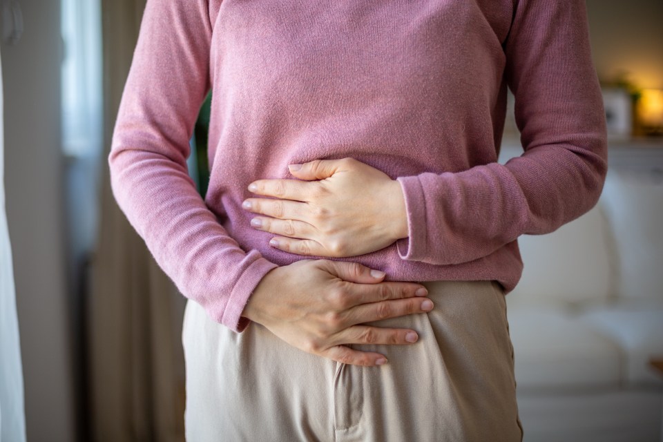 Woman holding her belly due to abdominal pain.