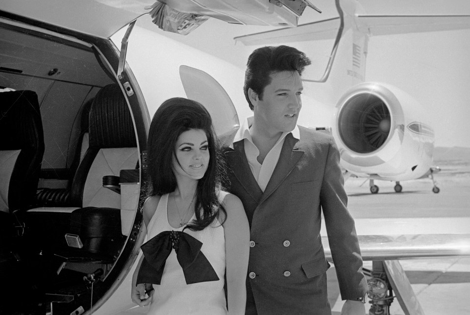 Newlyweds Elvis and Priscilla Presley pose next to a private jet.