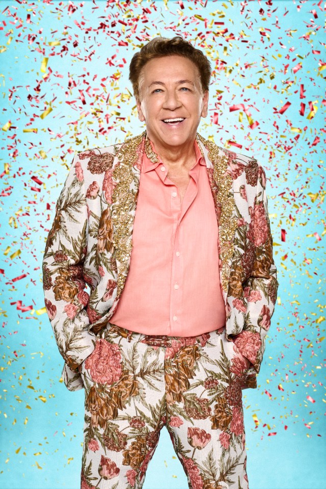Ross King smiling, wearing a floral suit with gold embellishments, with confetti falling around him.